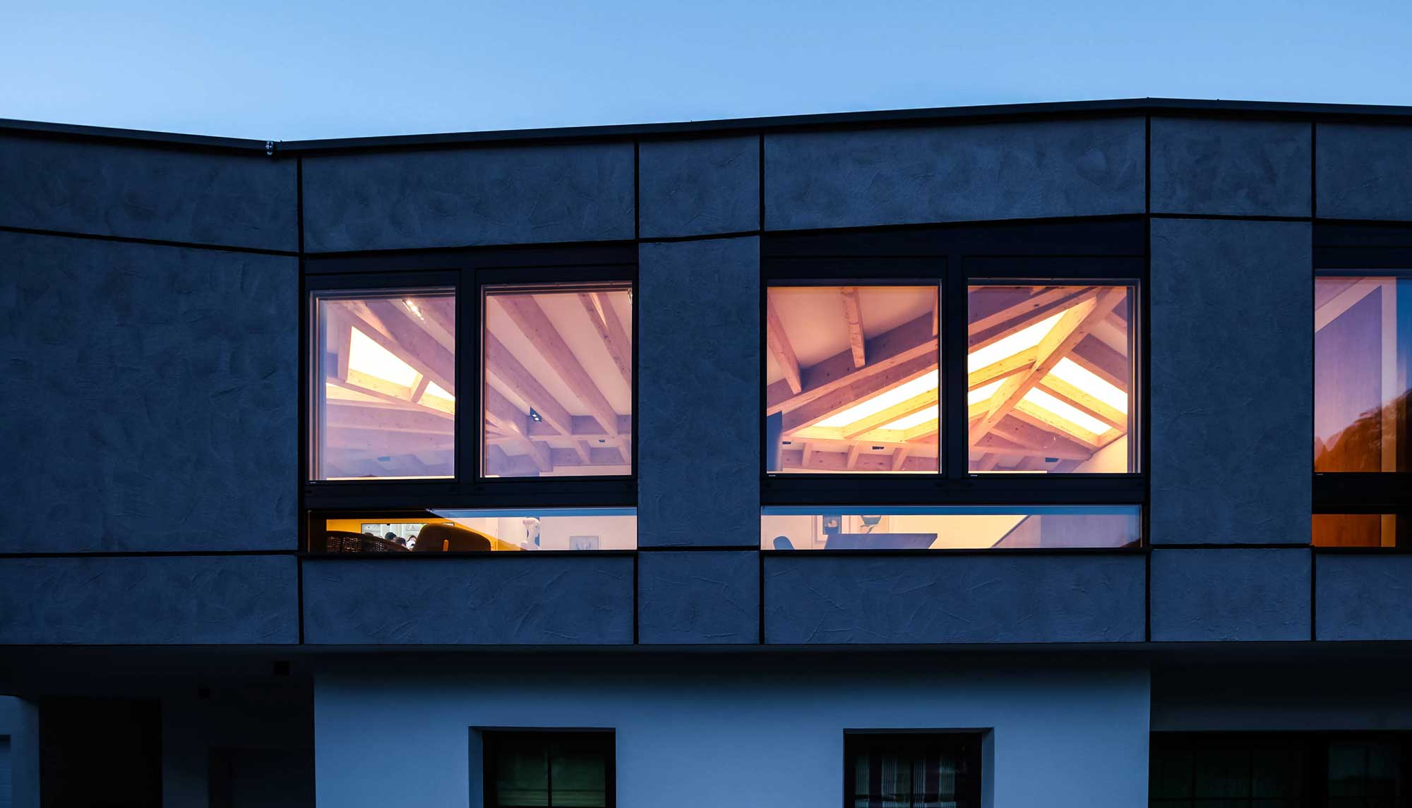 Licht strahlt durchs Fenster bei Dunkelheit und Dachstuhl kommt zur Geltung | Aufstockung Architekt