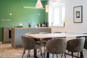 Appartement in Scharnitz – offene Wohnküche mit grüner Wand, Küchenzeile mit Holzkante und Esstisch für sechs Personen