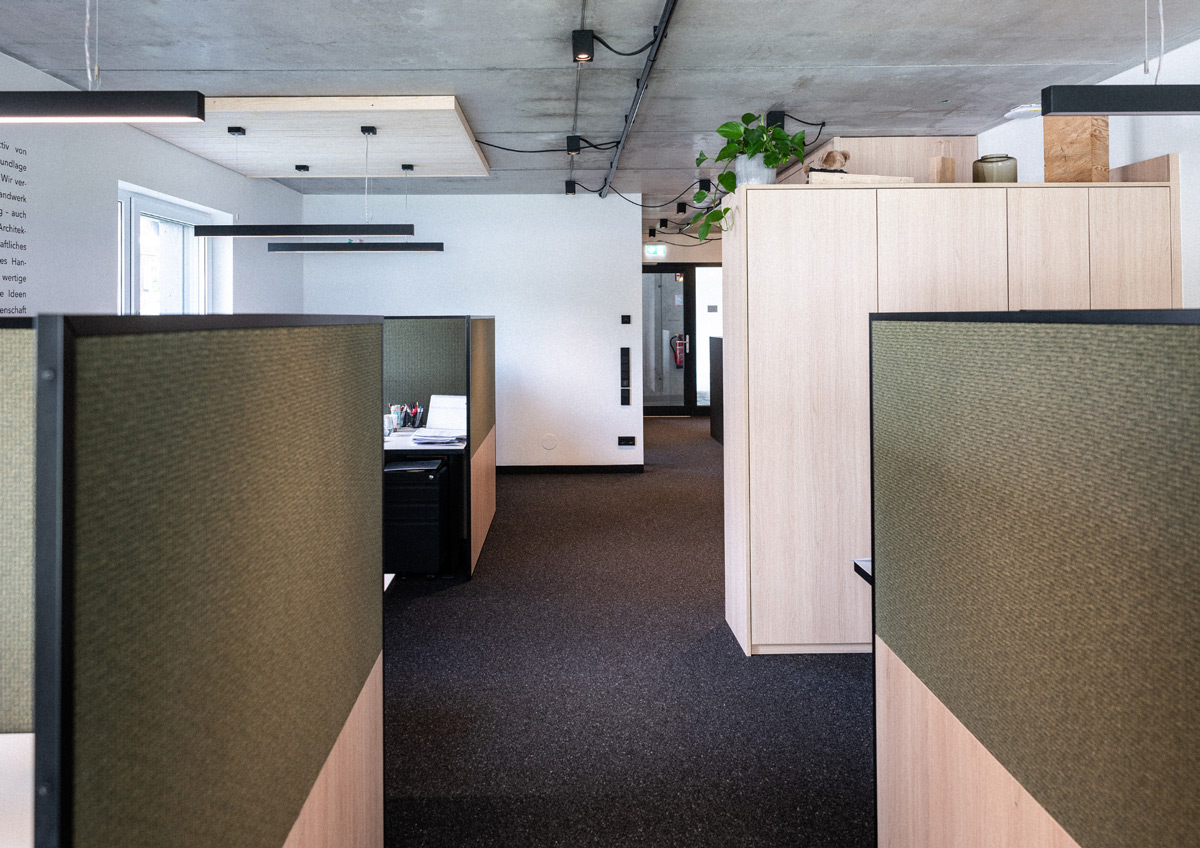 Büroplatz Moosburg – Fixdesk im Co-Working der SNOW Architektur Büroraum mit Fixdesk-Arbeitsplätzen, olivgrünen Trennwänden und Einbauschränken aus hellem Holz in der SNOW-Zweigstelle Moosburg bei Klagenfurt