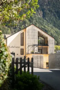 Lebe'oetz Oetz – Außenansicht mit Naturholzfassade Ferienapartmenthaus Lebe'oetz in Oetz: Neubau mit vertikaler Holzfassade, eingeschnittener Loggia und bewaldetem Hang im Hintergrund