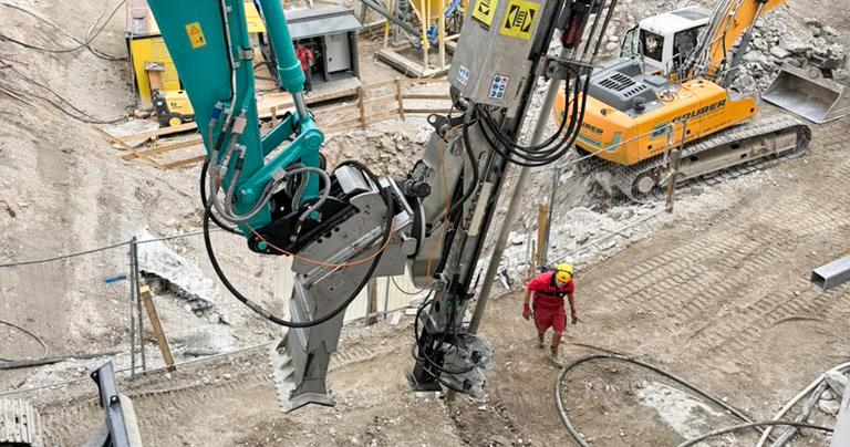 Bohrgerät beim Spezialtiefbau für die Tiefgarage der Nachverdichtung in Innsbruck, im Hintergrund Bagger und gelbe Silos